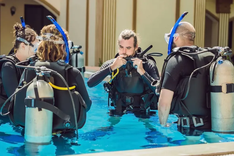 Des plongeurs en formation dans une piscine, vérification de l'équipement