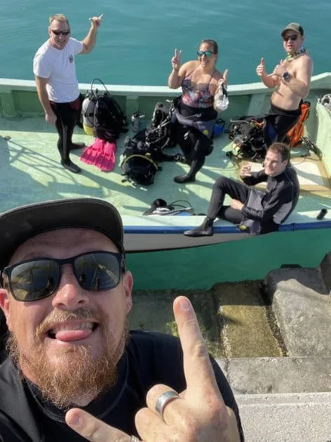 Plongeurs souriants sur un bateau vert, équipement de plongée visible