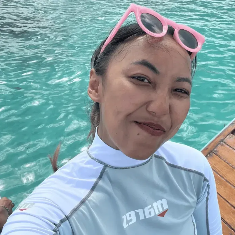 Jeune femme souriante en rashguard sur un bateau en mer