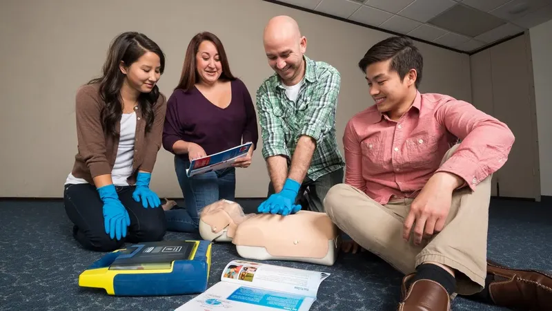 Quatre personnes suivent une formation de premiers secours avec un mannequin