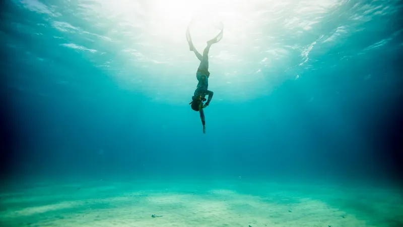 Apnée : une personne plonge verticalement dans une eau turquoise claire