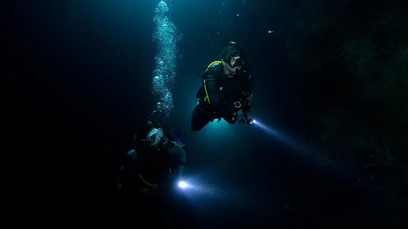 Deux plongeurs avec lampes torche explorent les profondeurs marines sombres