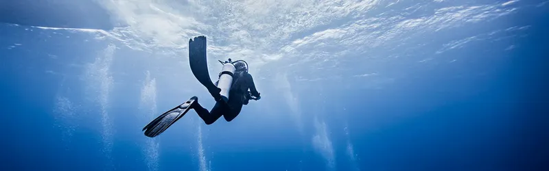 Plongeur en combinaison noire nageant dans une eau bleue claire