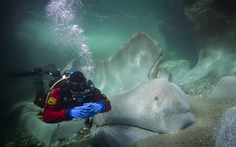 Plongeur explorant un paysage rocheux sous-marin avec des bulles