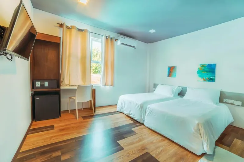 Chambre d'hôtel lumineuse avec deux lits simples et bureau