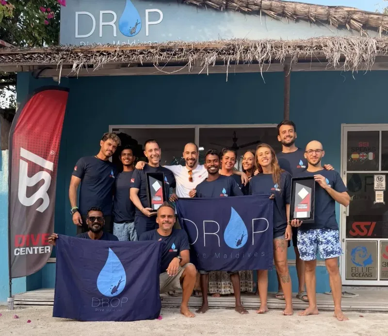 Groupe de personnes souriantes devant la façade d'un centre de plongée