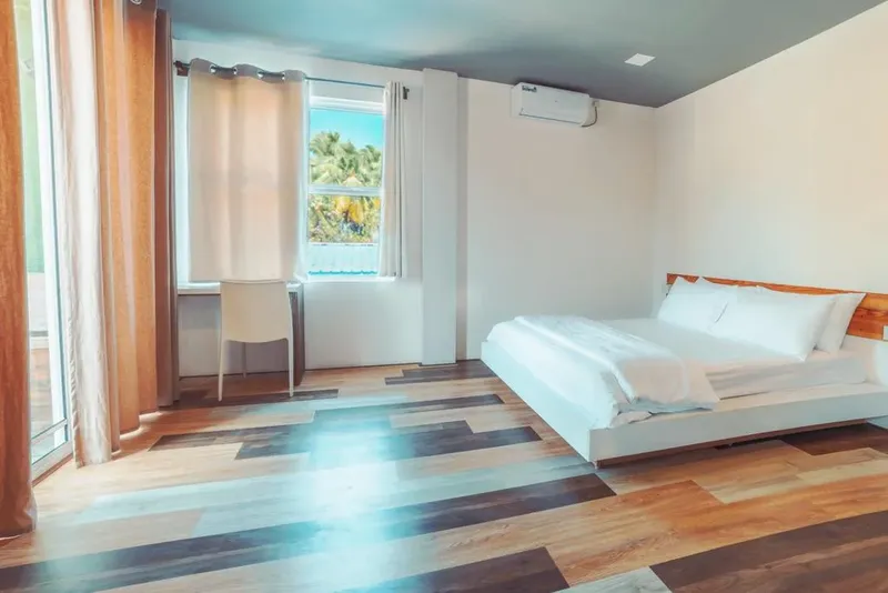 Chambre d'hôtel lumineuse avec un grand lit blanc et vue sur l'extérieur