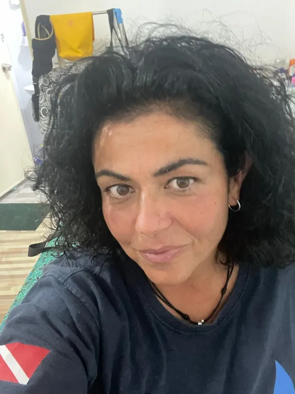 Portrait d'une femme souriante avec des cheveux bouclés et un t-shirt
