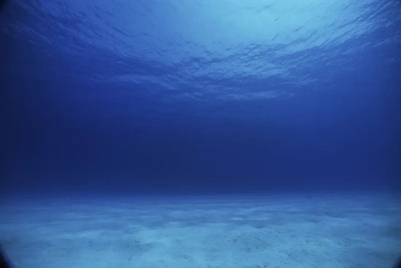 Vue sous-marine d'un fond sableux bleu clair avec la surface