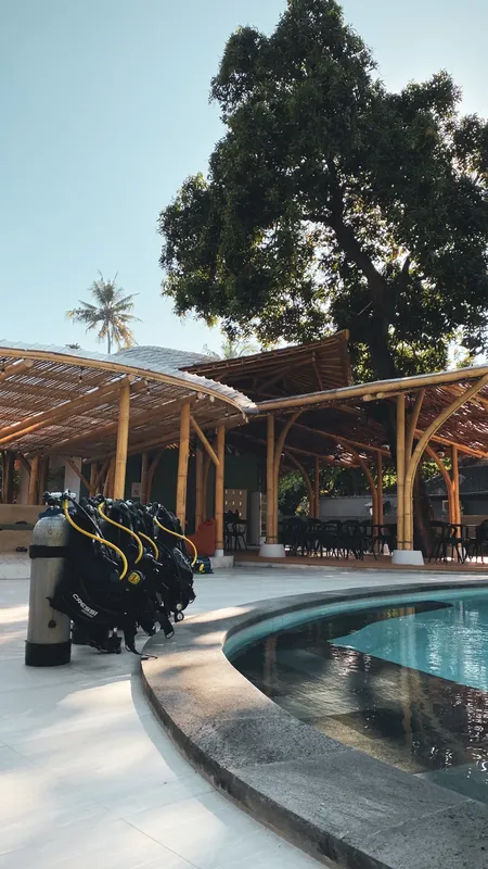 Bouteilles de plongée devant une structure en bois et une piscine