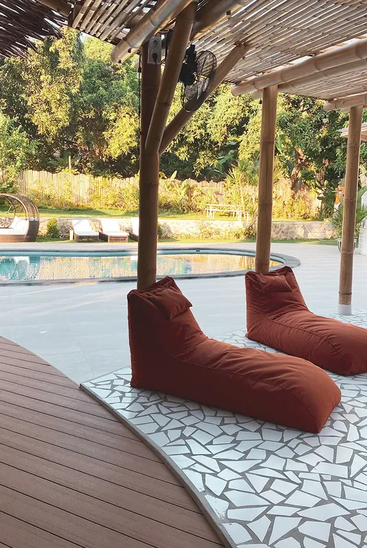 Espace détente avec deux fauteuils poire près d'une piscine ensoleillée