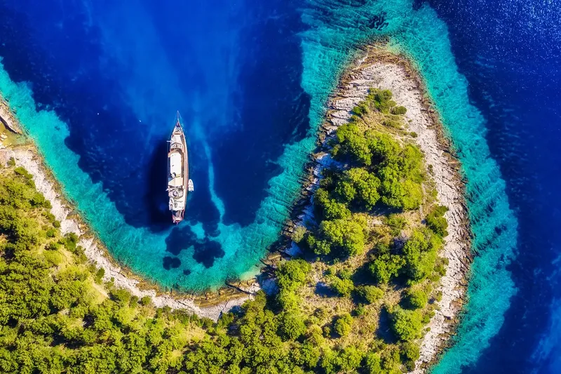 Vue aérienne d'un bateau naviguant près d'une côte rocheuse turquoise