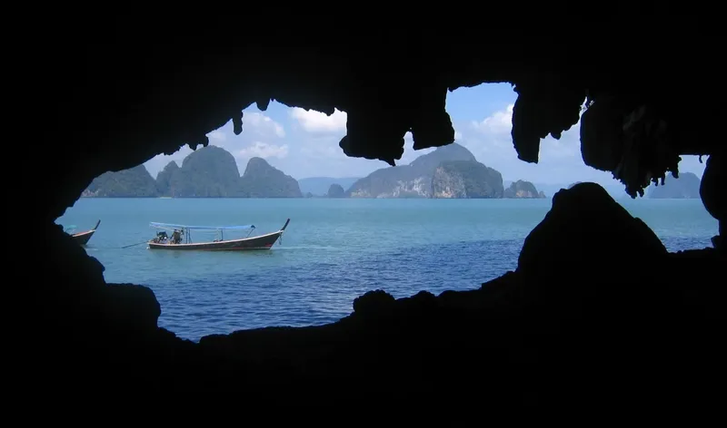 Bateau longtail traditionnel navigue dans une baie turquoise entre îles