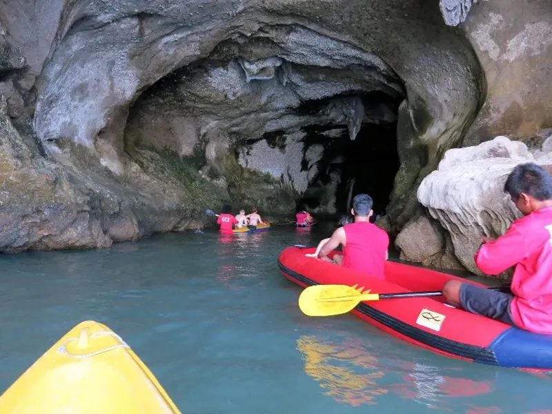 Personnes en kayak explorent une grotte marine rocheuse turquoise