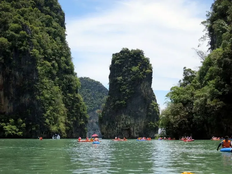 Personnes en kayak dans une lagune entre des falaises verdoyantes