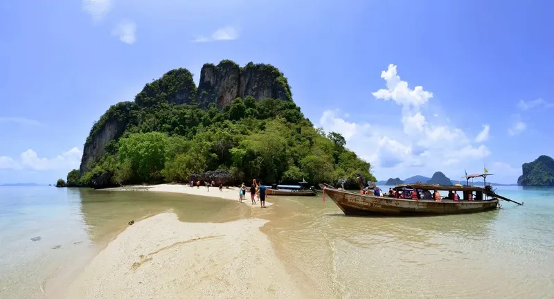 Plage de sable blanc, longtail boat et personnes sur une île tropicale