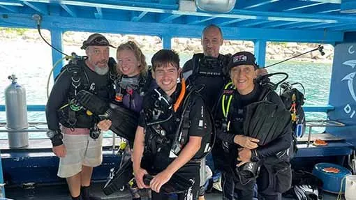 Groupe de plongeurs souriants équipés à bord d'un bateau de plongée