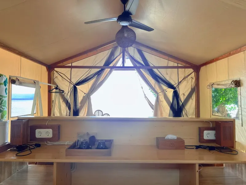Intérieur d'une cabane en bois avec vue sur la mer et ventilateur