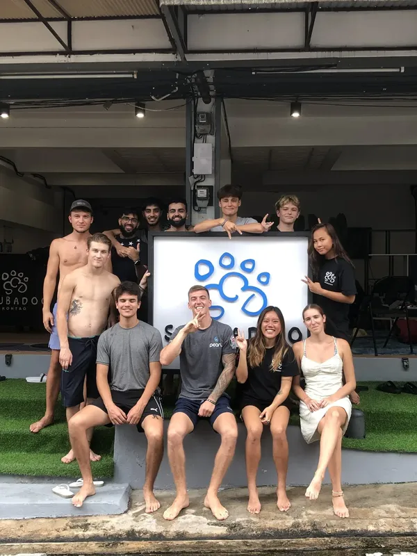 Groupe de personnes souriantes posant devant un mur décoré d'un motif bleu