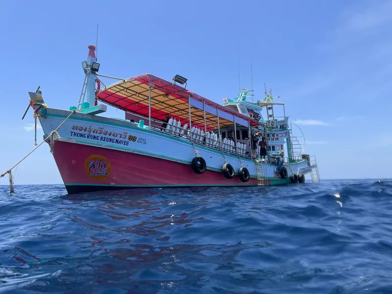 Bateau de plongée coloré navigue sur une mer bleue calme