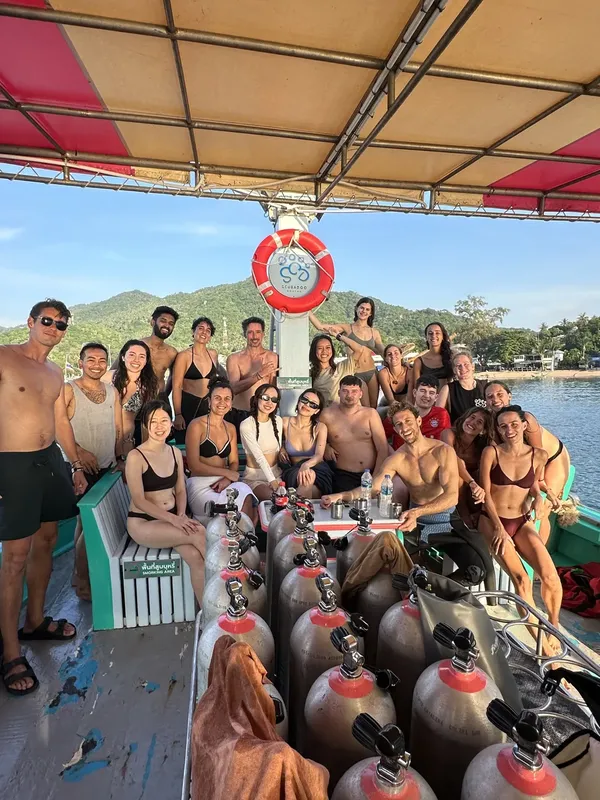 Groupe de plongeurs souriants sur un bateau avec des bouteilles