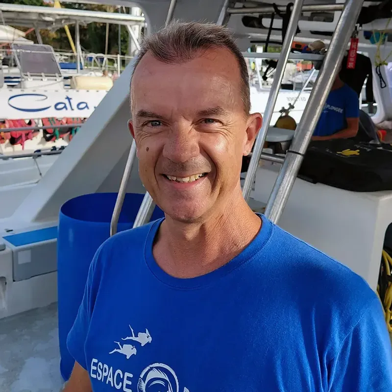 Homme souriant sur un bateau de plongée, portant un t-shirt bleu
