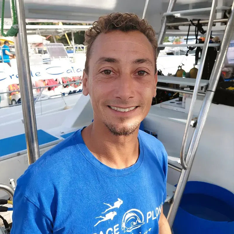 Homme souriant sur un bateau avec d'autres bateaux en arrière-plan