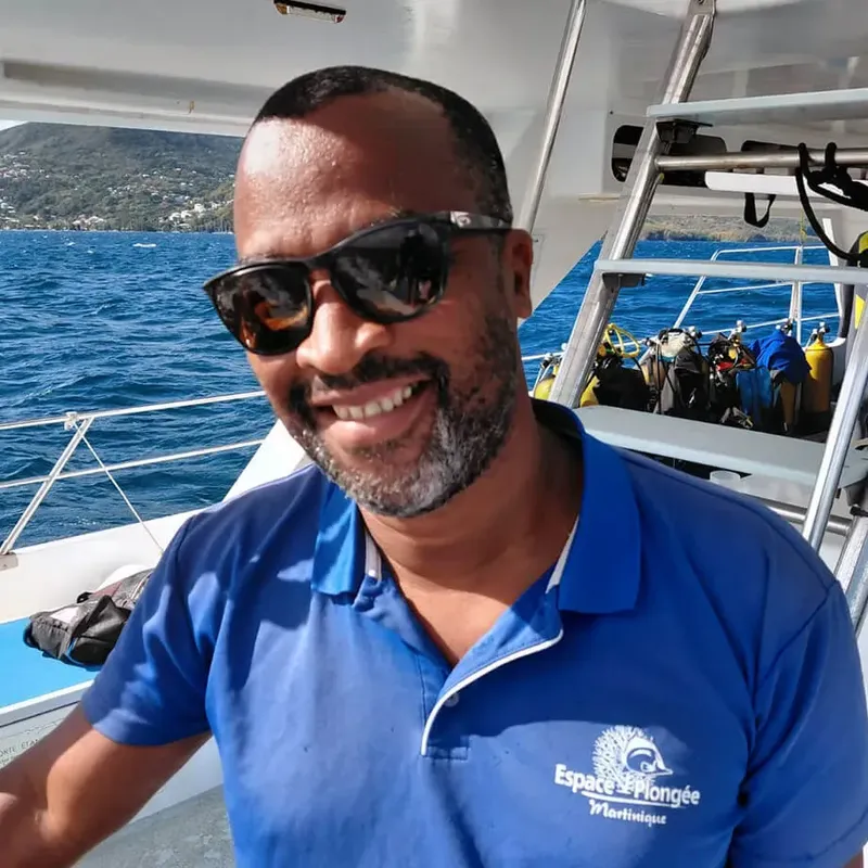 Homme souriant sur un bateau de plongée en mer turquoise