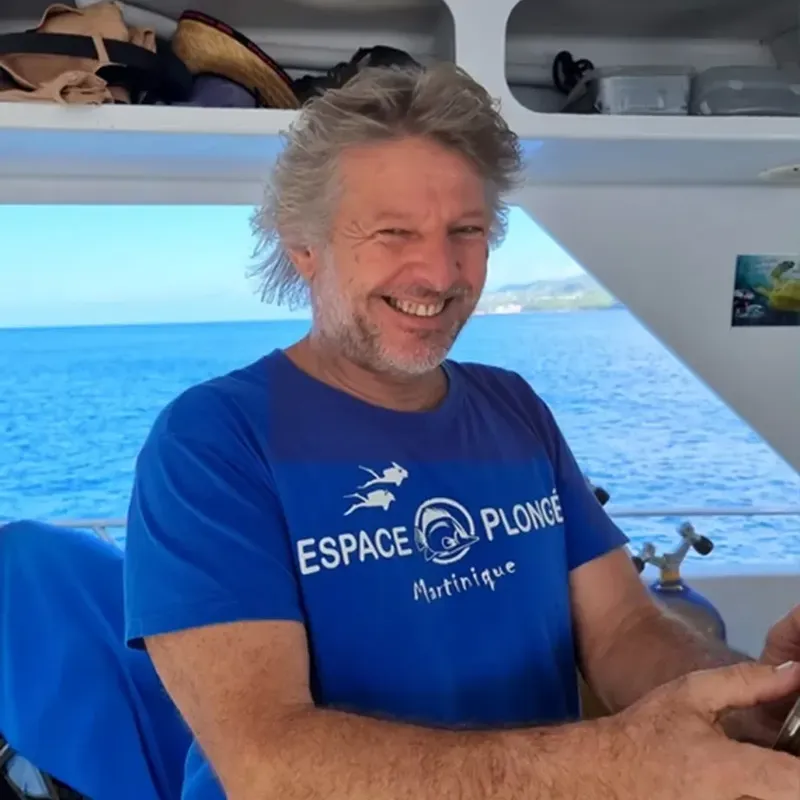 Plongeur souriant en mer, portant un t-shirt bleu avec un logo