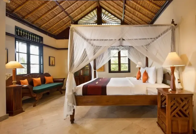 Chambre d'hôtel avec lit à baldaquin et décoration tropicale