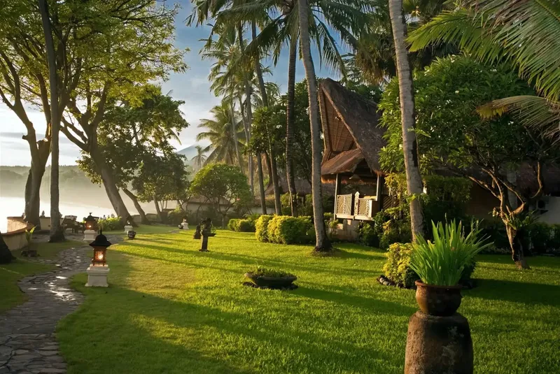 Jardin tropical luxuriant avec bâtiments traditionnels au bord de l'eau