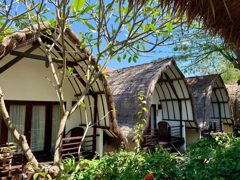 Petites maisons de style colonial avec toits de chaume et végétation tropicale
