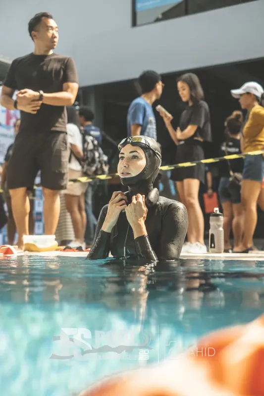 Plongeuse en combinaison noire se préparant au bord d'une piscine