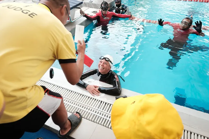 Des plongeurs en formation dans une piscine, sourires et gestes techniques