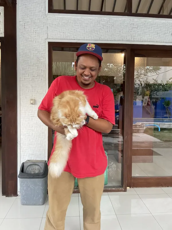 Un homme souriant tient un grand chat roux dans ses bras