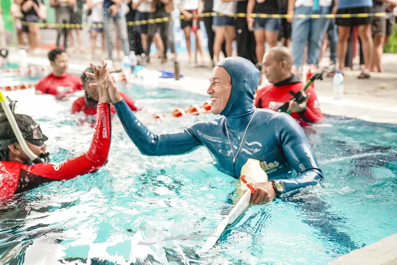 Plongeur émergeant d'une piscine, célébrant avec un autre nageur