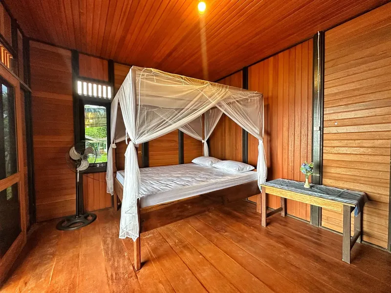 Chambre en bois avec lit à baldaquin et petite table de chevet