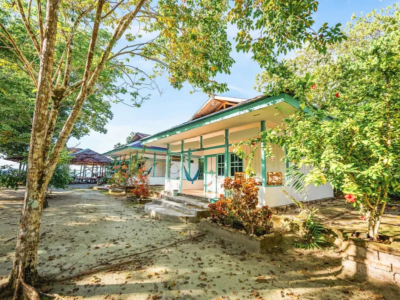 Bâtiment blanc avec végétation tropicale et hamac sur une terrasse