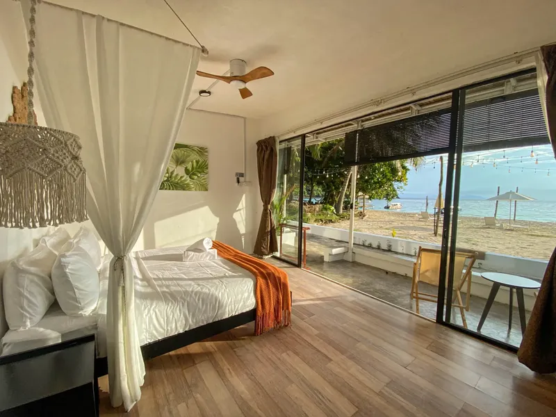 Chambre avec lit à baldaquin donnant sur une plage ensoleillée