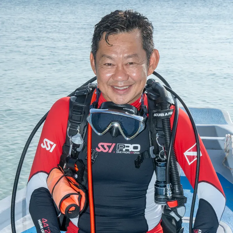 Plongeur souriant en combinaison, équipé, sur un bateau de plongée