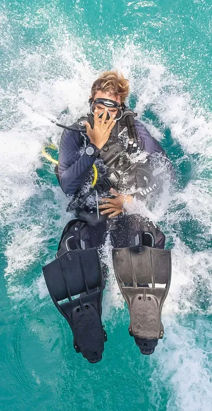 Plongeur en équipement complet, flottant à la surface de l'eau turquoise