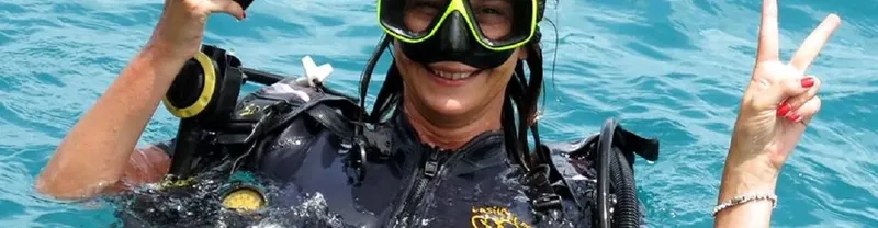 Plongeuse souriante avec masque et combinaison dans l'eau turquoise