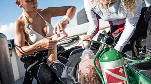 Secourisme : deux personnes soignent un homme allongé sur un bateau
