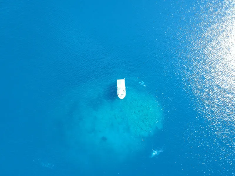 Vue aérienne d'un bateau blanc sur une eau turquoise claire