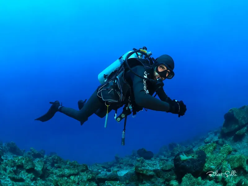 Plongeur en combinaison explore un récifal sous-marin bleu profond