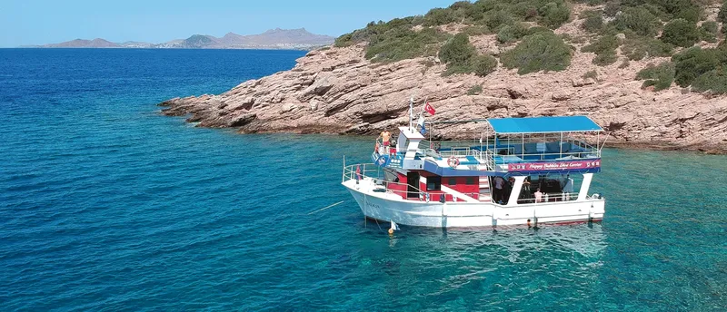Bateau de plongée amarré dans une crique rocheuse ensoleillée mer bleue