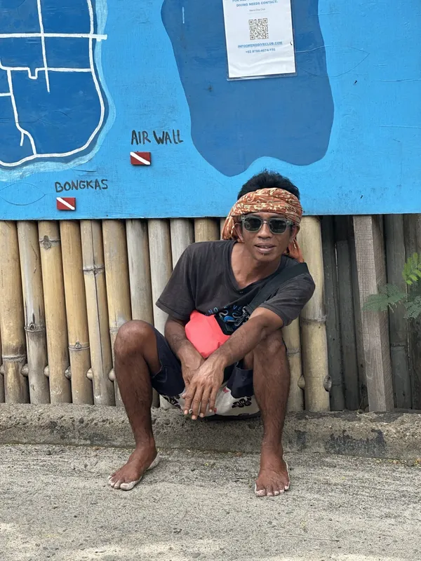 Homme accroupi devant un mur bleu avec des dessins de plongée