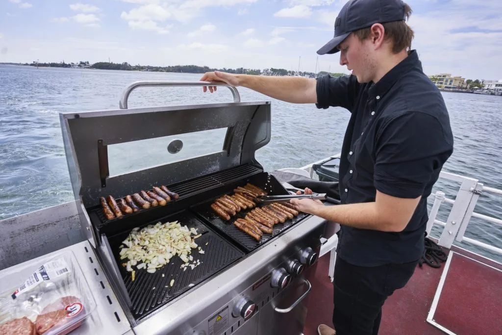 Un homme cuisine des brochettes sur un barbecue à bord d'un bateau