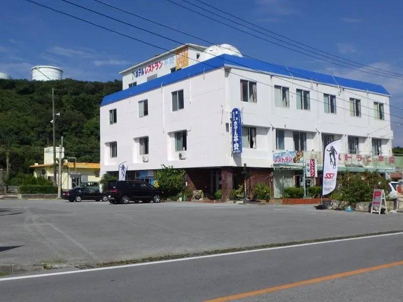 Bâtiment blanc à deux étages avec enseignes et parking devant