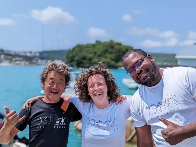 Trois personnes souriantes sur un bateau en mer, journée ensoleillée